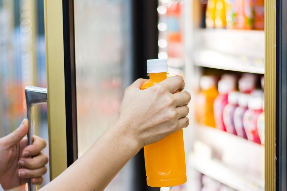 A Person Is Holding A Bottle Of Orange Juice — Jordan Wheatland Air Conditioning & Refrigeration In Dubbo, NSW