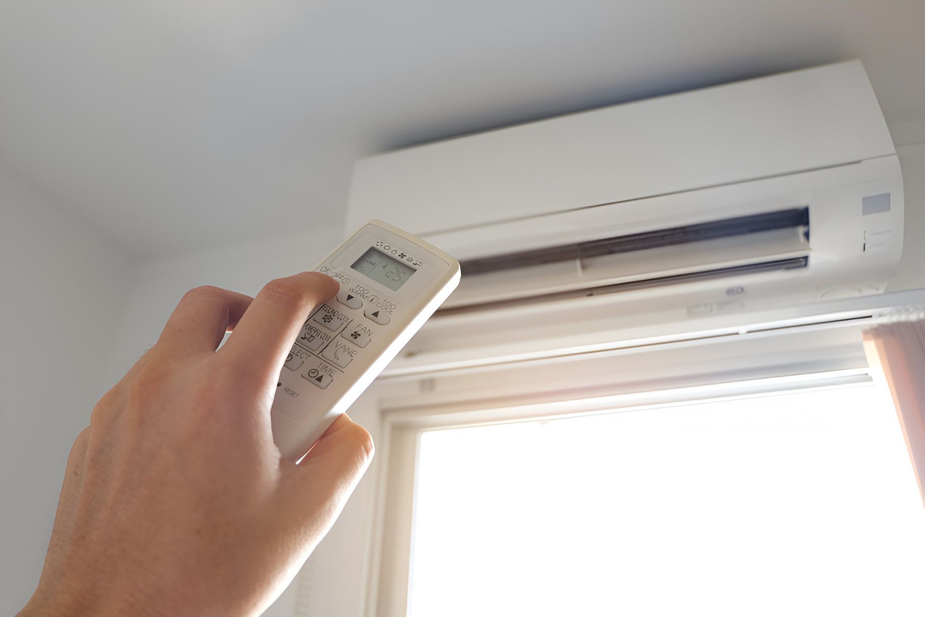 A Person Is Holding A Remote Control — Jordan Wheatland Air Conditioning & Refrigeration In Condobolin, NSW