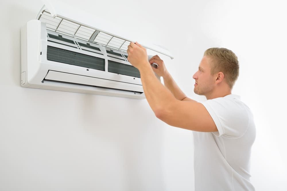 A Man Is Cleaning An Ac — Jordan Wheatland Air Conditioning & Refrigeration In Dubbo, NSW