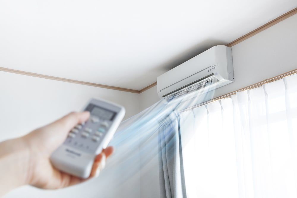 A Person Is Holding A Remote — Jordan Wheatland Air Conditioning & Refrigeration In Dubbo, NSW
