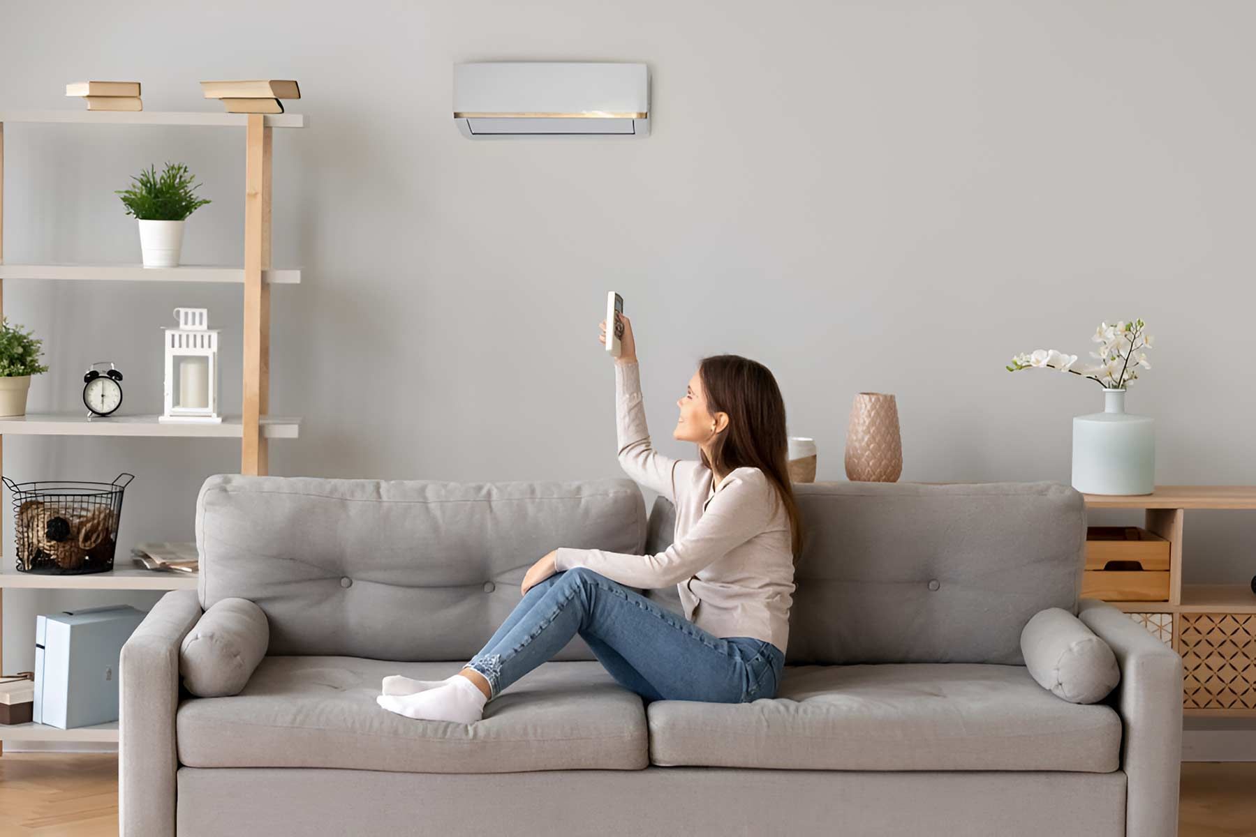 A Woman Is Sitting On A Couch Holding A Remote Control — Jordan Wheatland Air Conditioning & Refrigeration In Nyngan, NSW