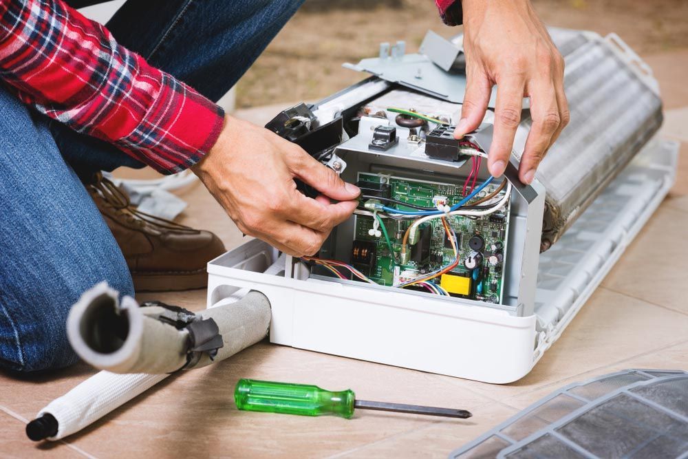 A Man Repairing An Air Conditioner On The Floor — Jordan Wheatland Air Conditioning & Refrigeration