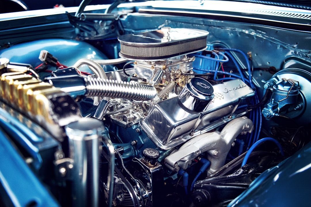 Close-up of a polished blue car engine with chrome valve covers, an air cleaner, and metallic components.