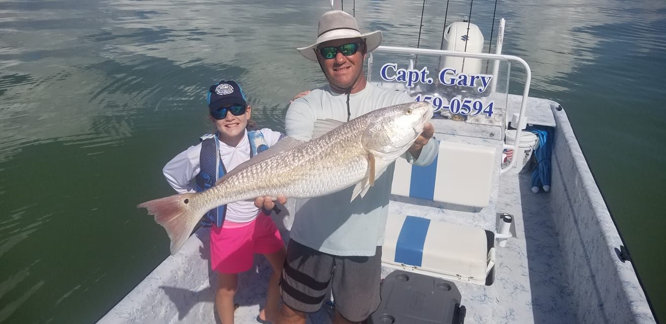 A man and a boy are standing on a boat holding a large fish.