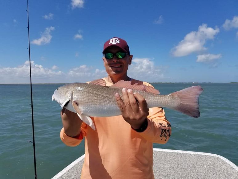 A man is holding a large fish on a boat.