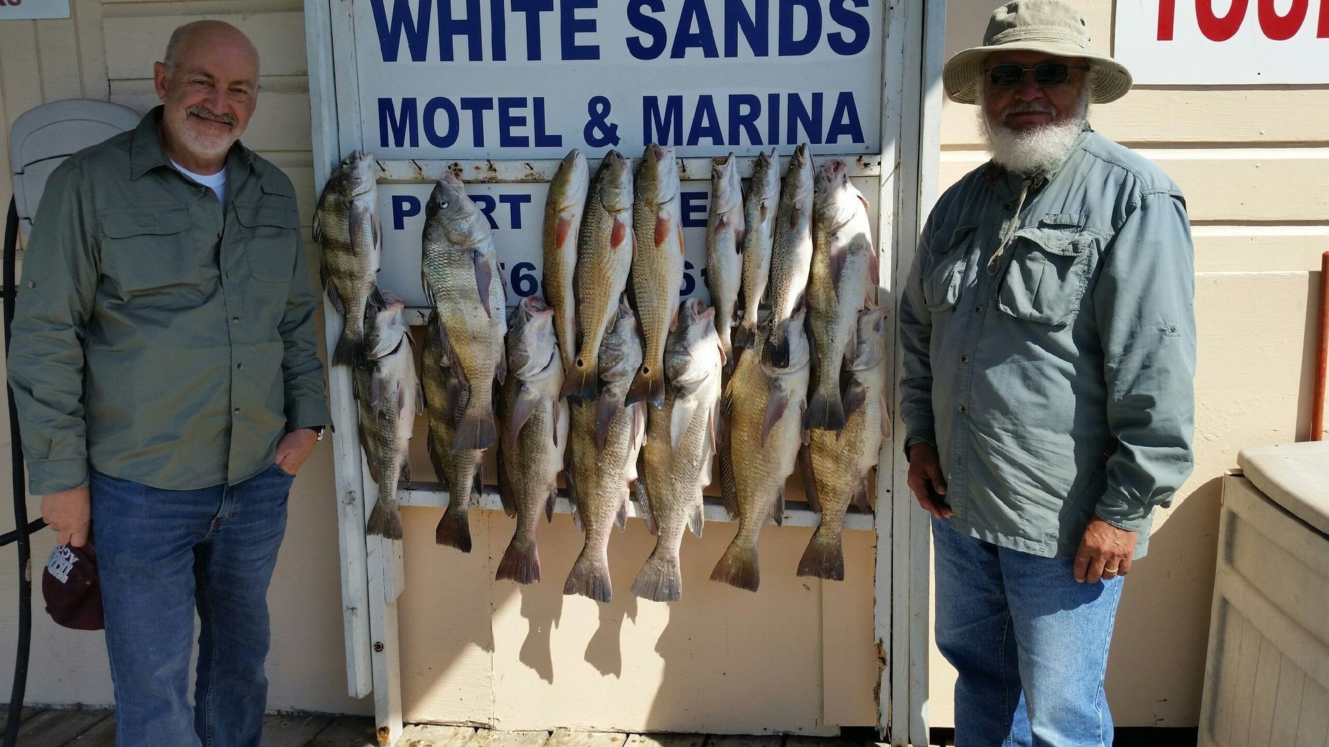 Two men standing in front of a sign that says white sands motel & marina