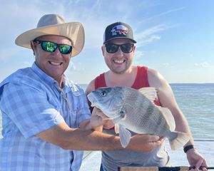 Two men are holding a large fish on a boat.