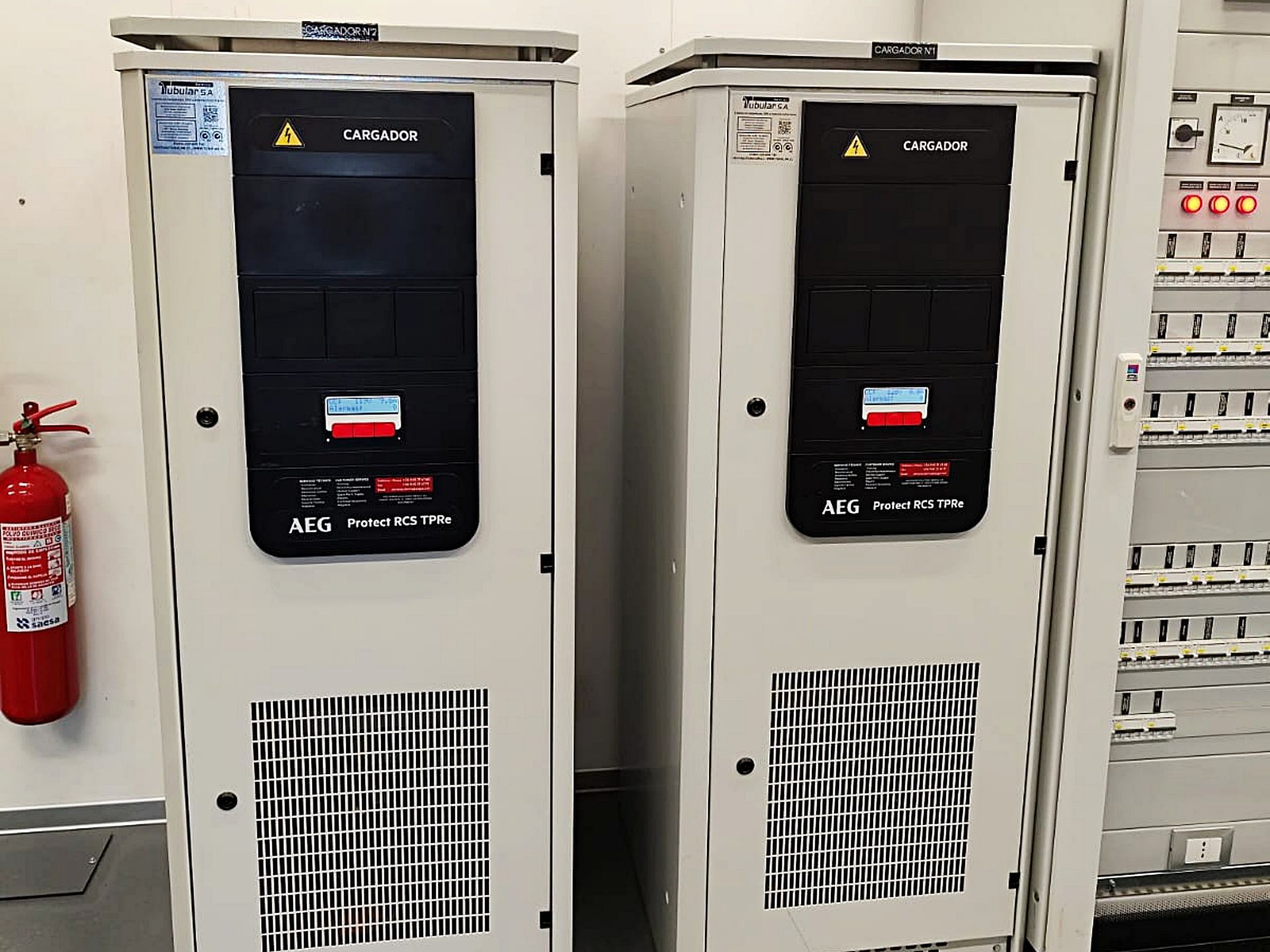Un extintor de incendios está al lado de dos armarios eléctricos.