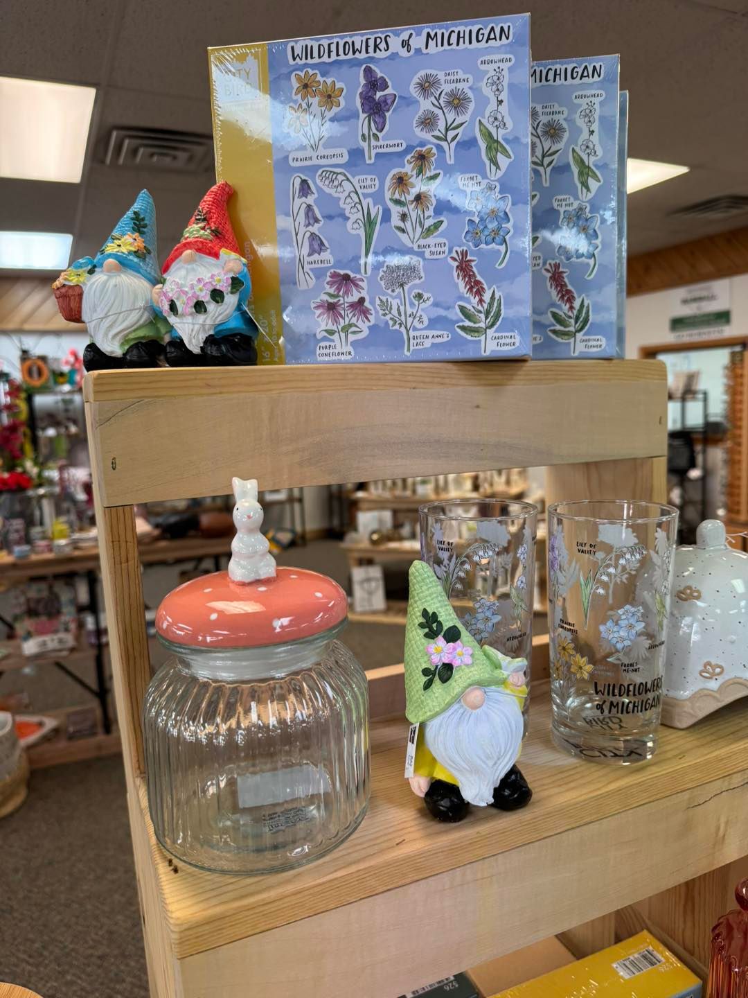 A shelf with gnomes , a jar , and a glass on it.