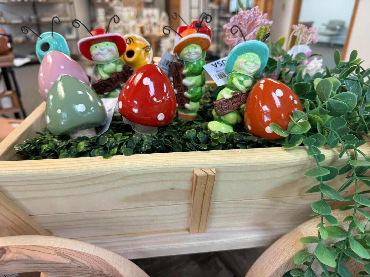 A wooden planter filled with ceramic bugs and mushrooms.