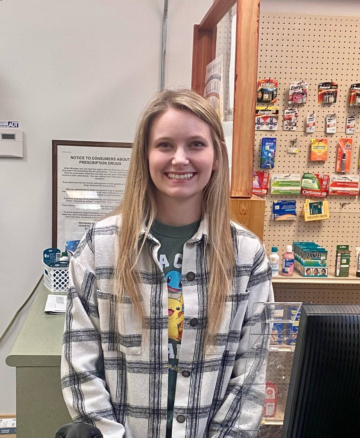 A woman in a plaid shirt is smiling in a store