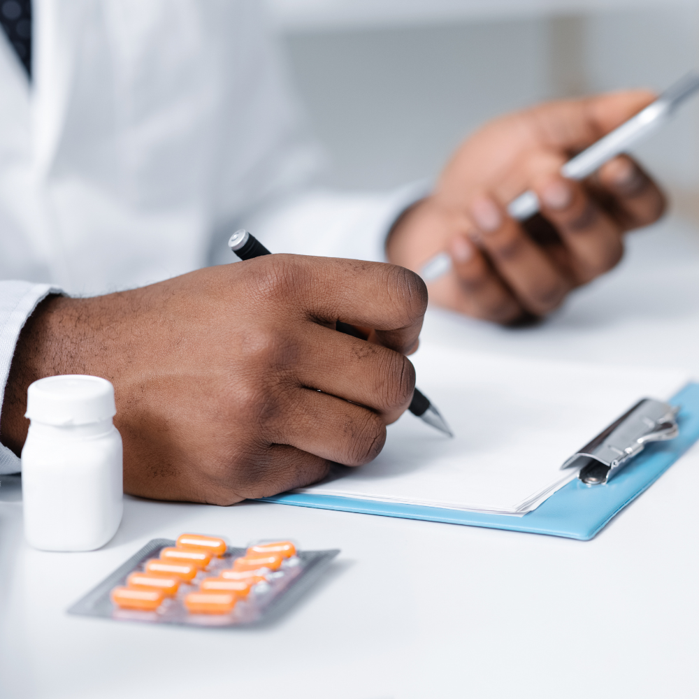 A doctor is writing on a clipboard next to a bottle of pills