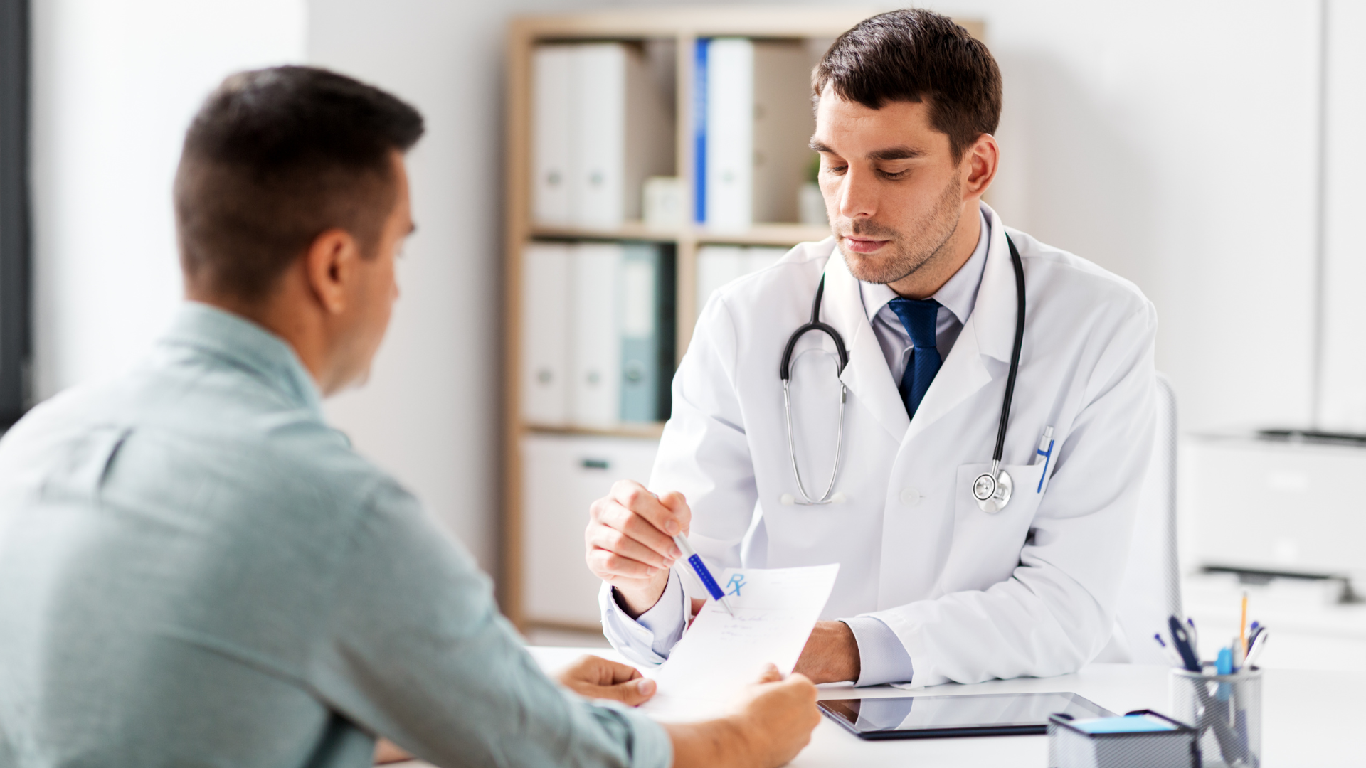 A doctor is talking to a patient while holding a piece of paper.