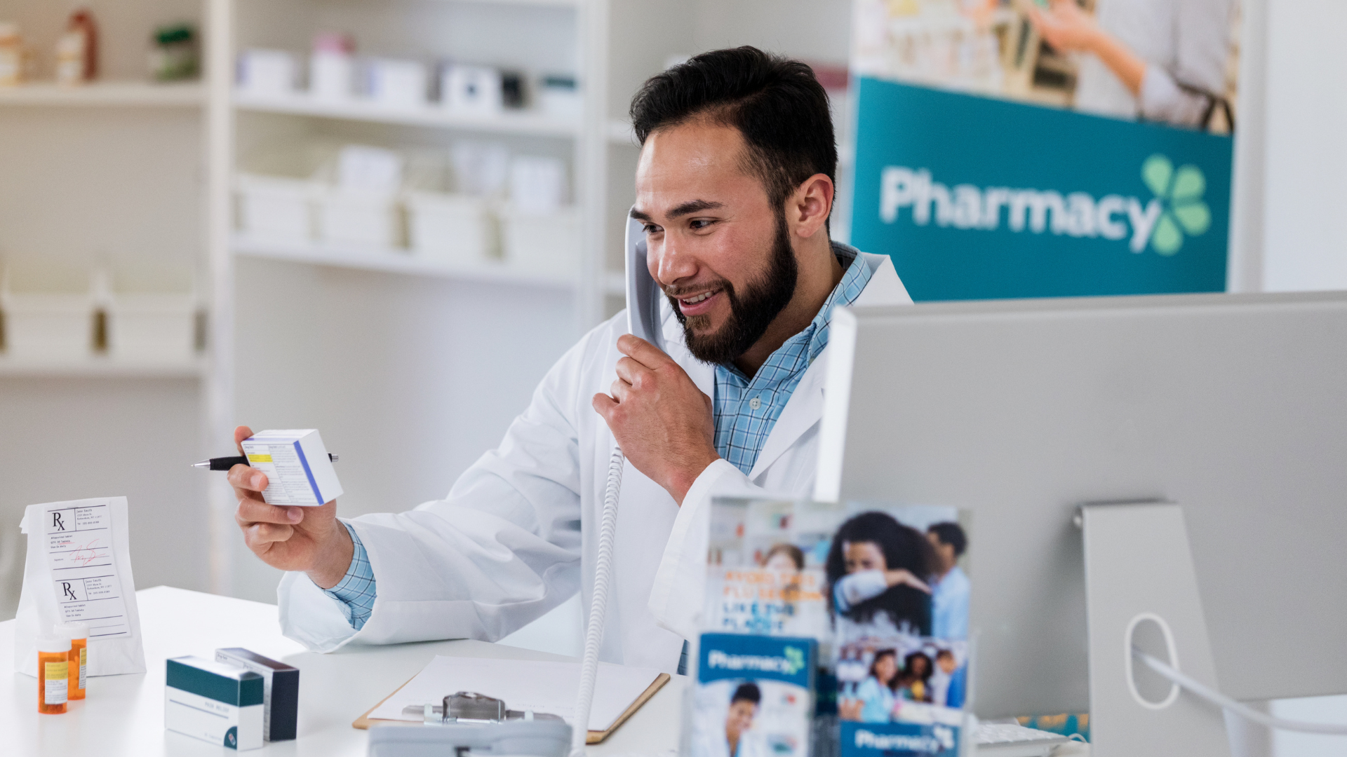 A pharmacist is talking on a cell phone while looking at a prescription.