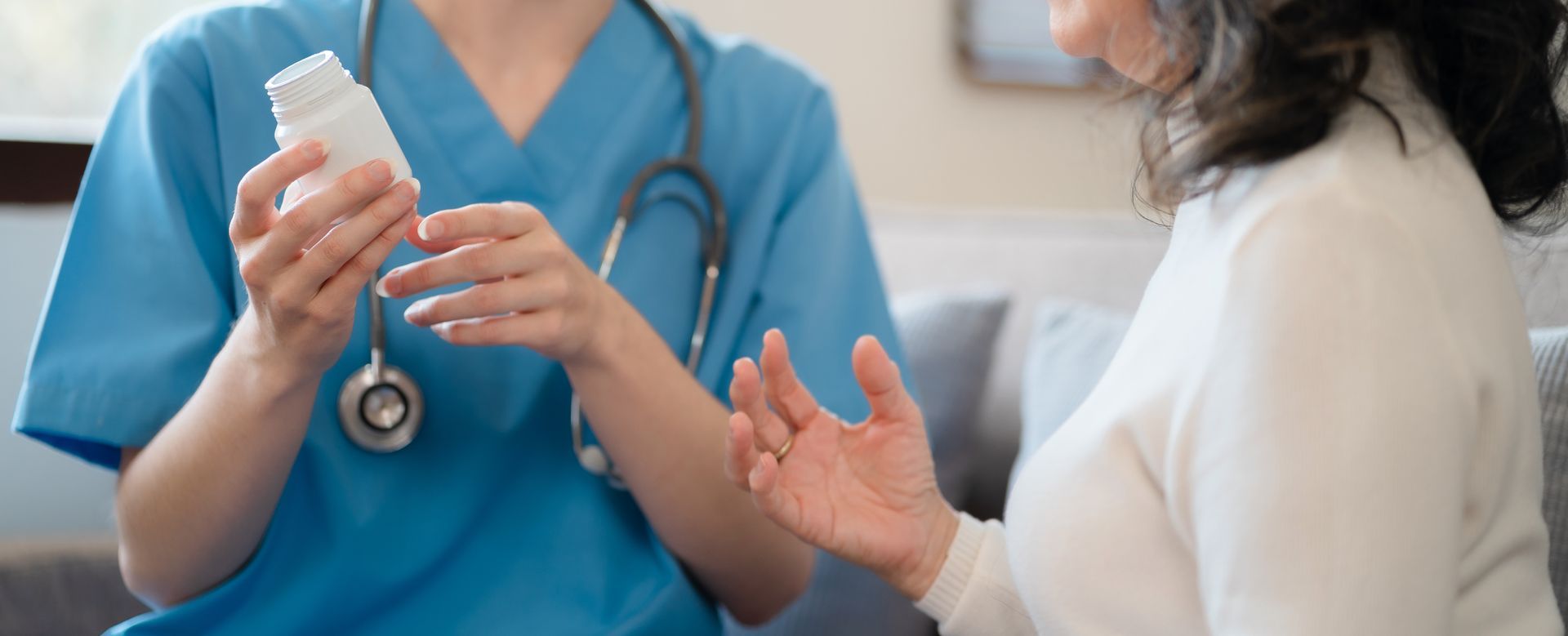 A nurse is holding a bottle of pills and talking to a patient.