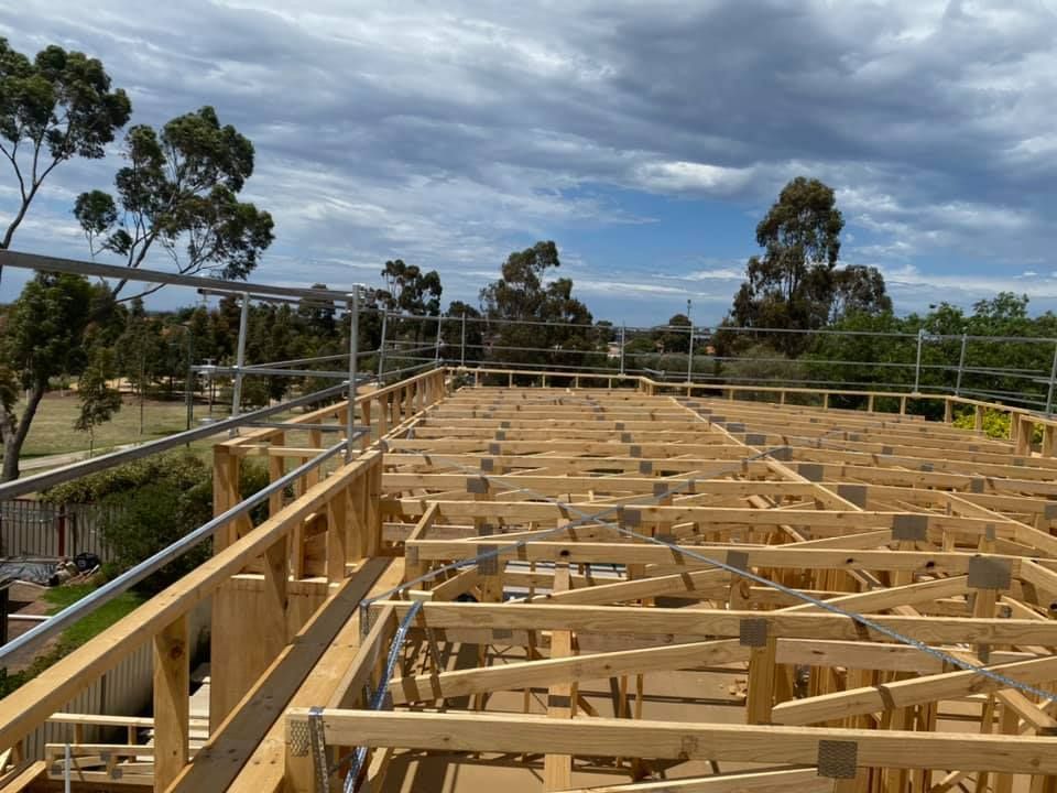 Construction site with wooden framing and scaffolding, building under construction on a sunny day.