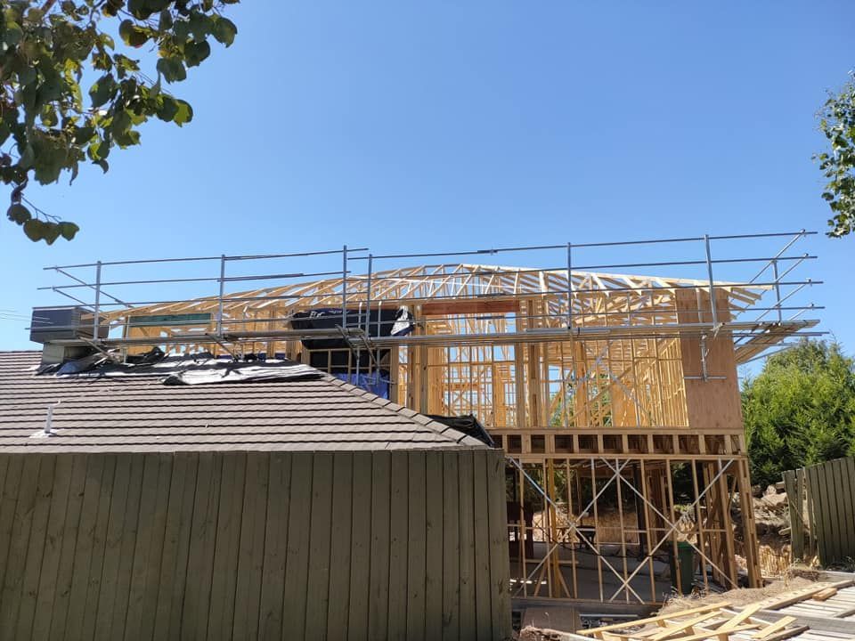 Construction site: new wooden frame house under construction with scaffolding, sunny day.