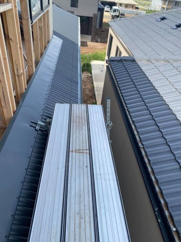 A construction worker on a rooftop, using a safety harness, alongside a platform.