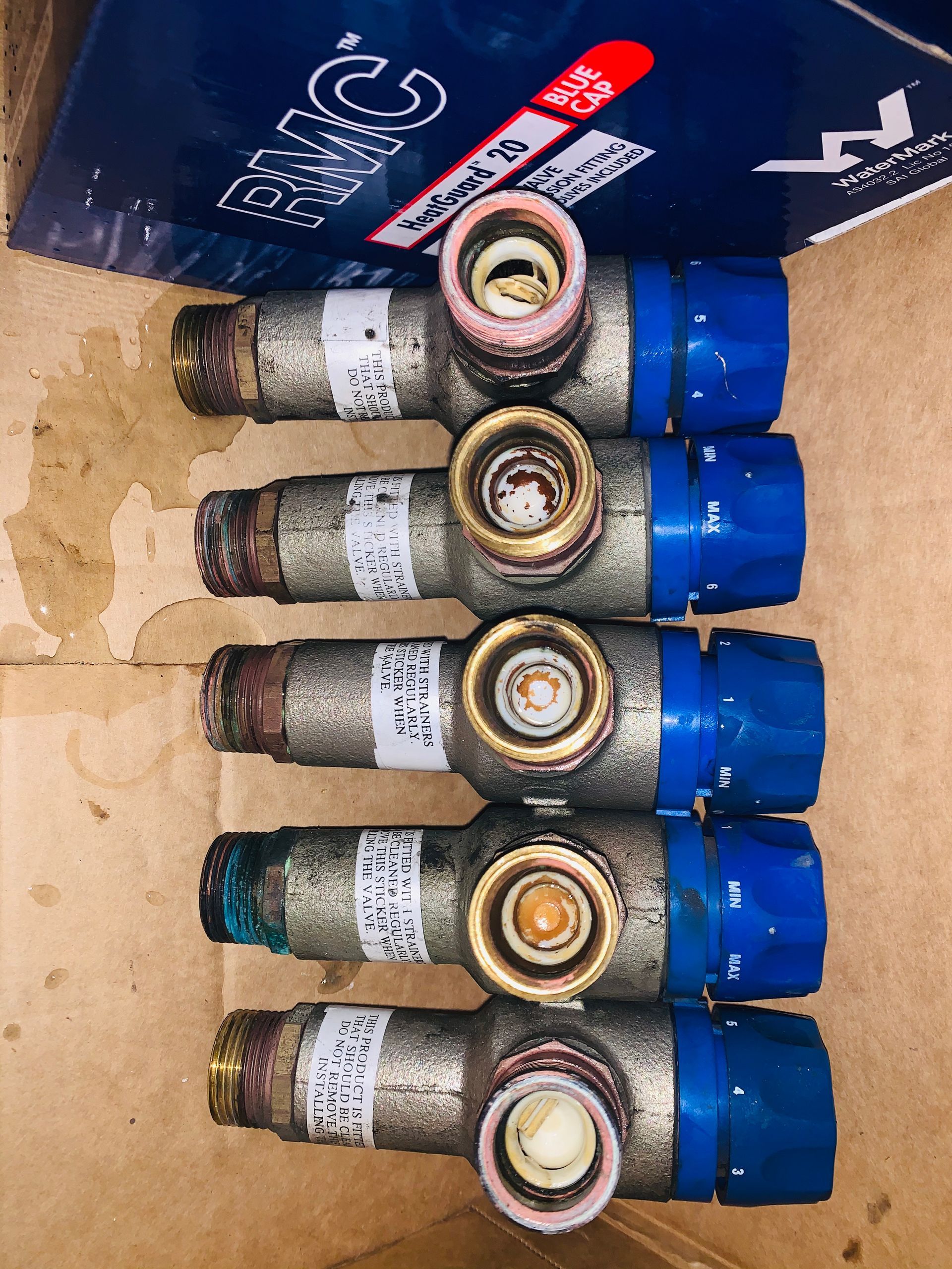 White water heater on a blue wall, with windows and a hose reel nearby.