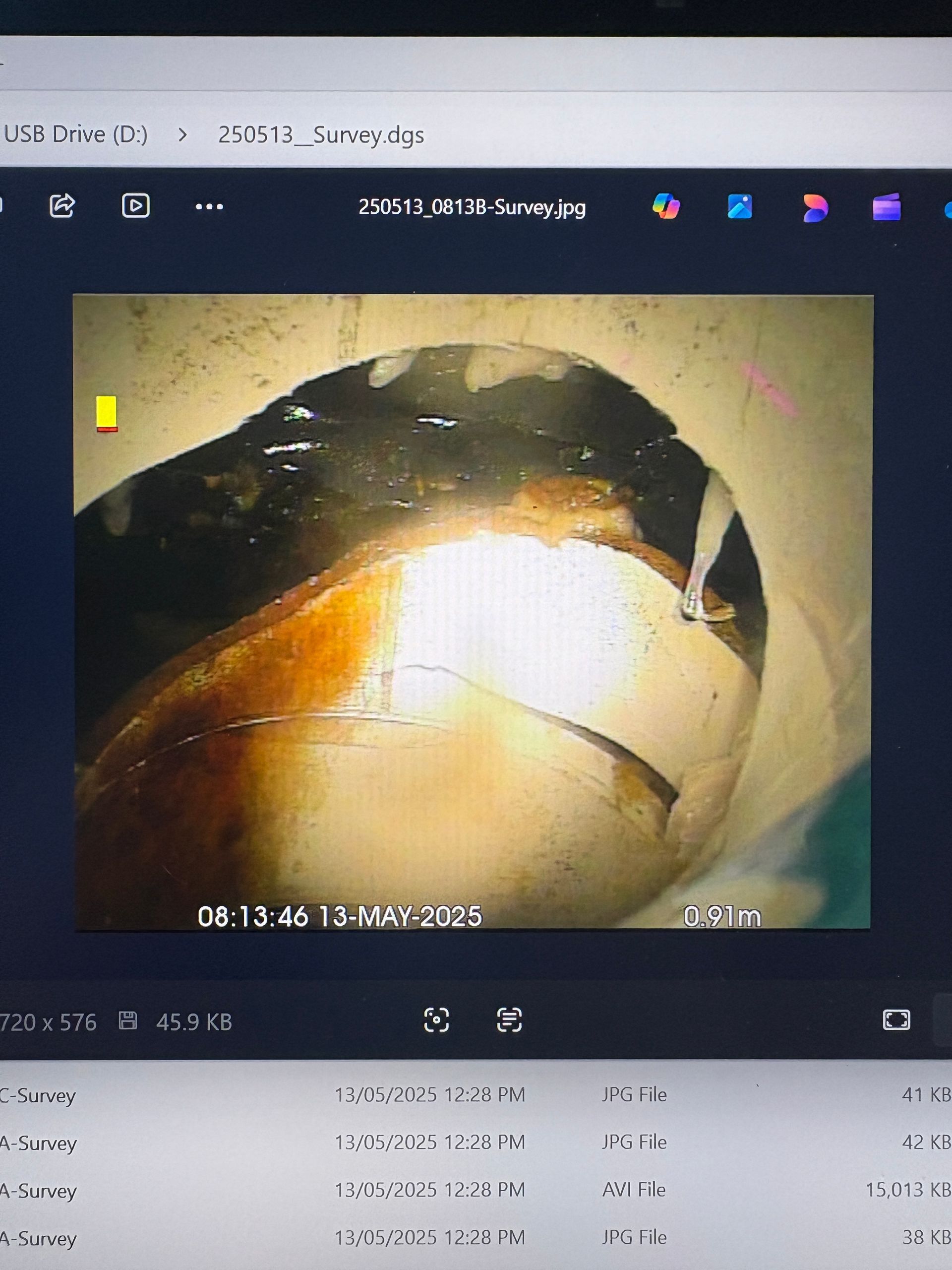 Submersible pump covered in white residue and cables, on a concrete surface.