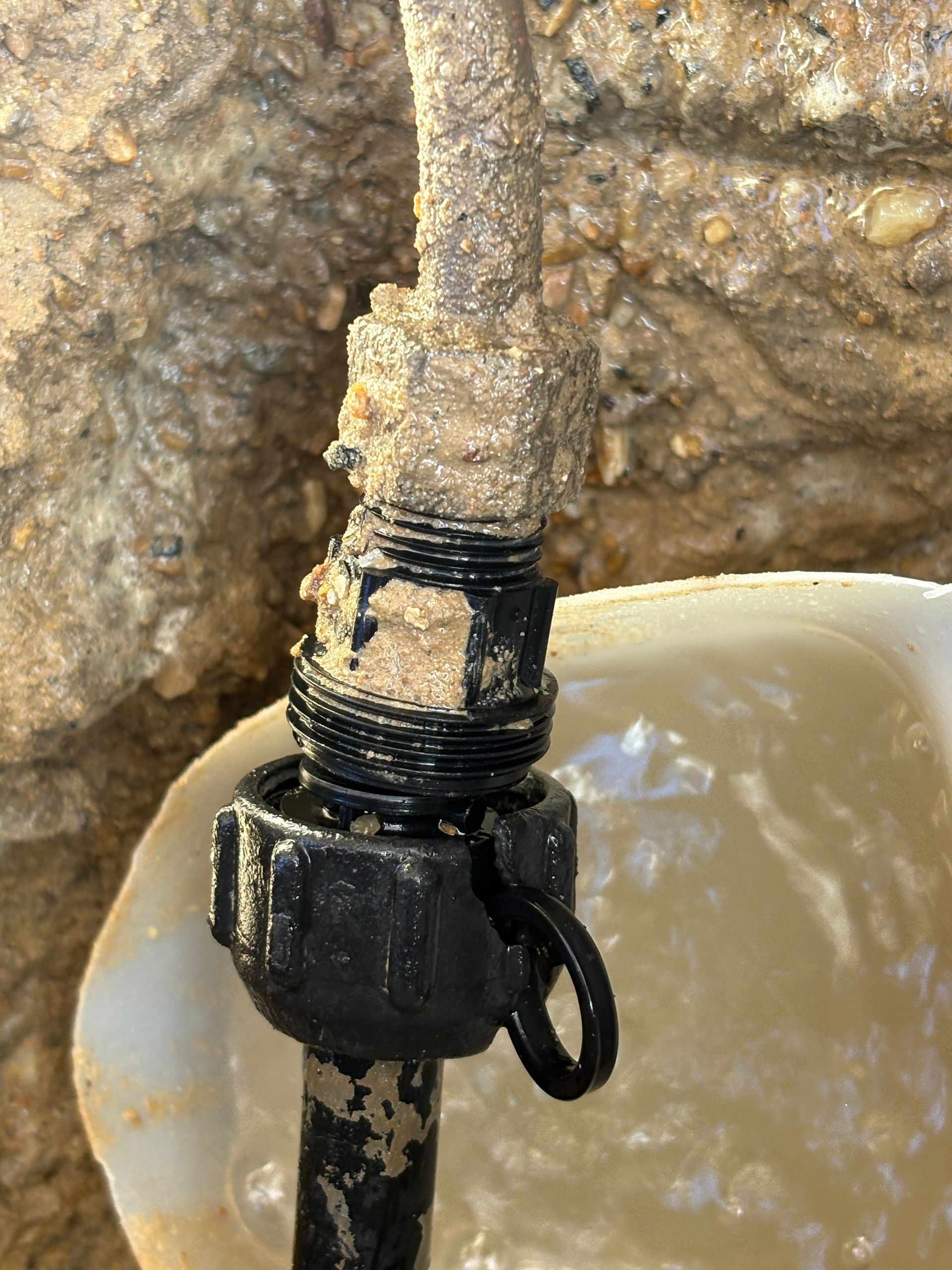 White water heater on a blue wall, with windows and a hose reel nearby.