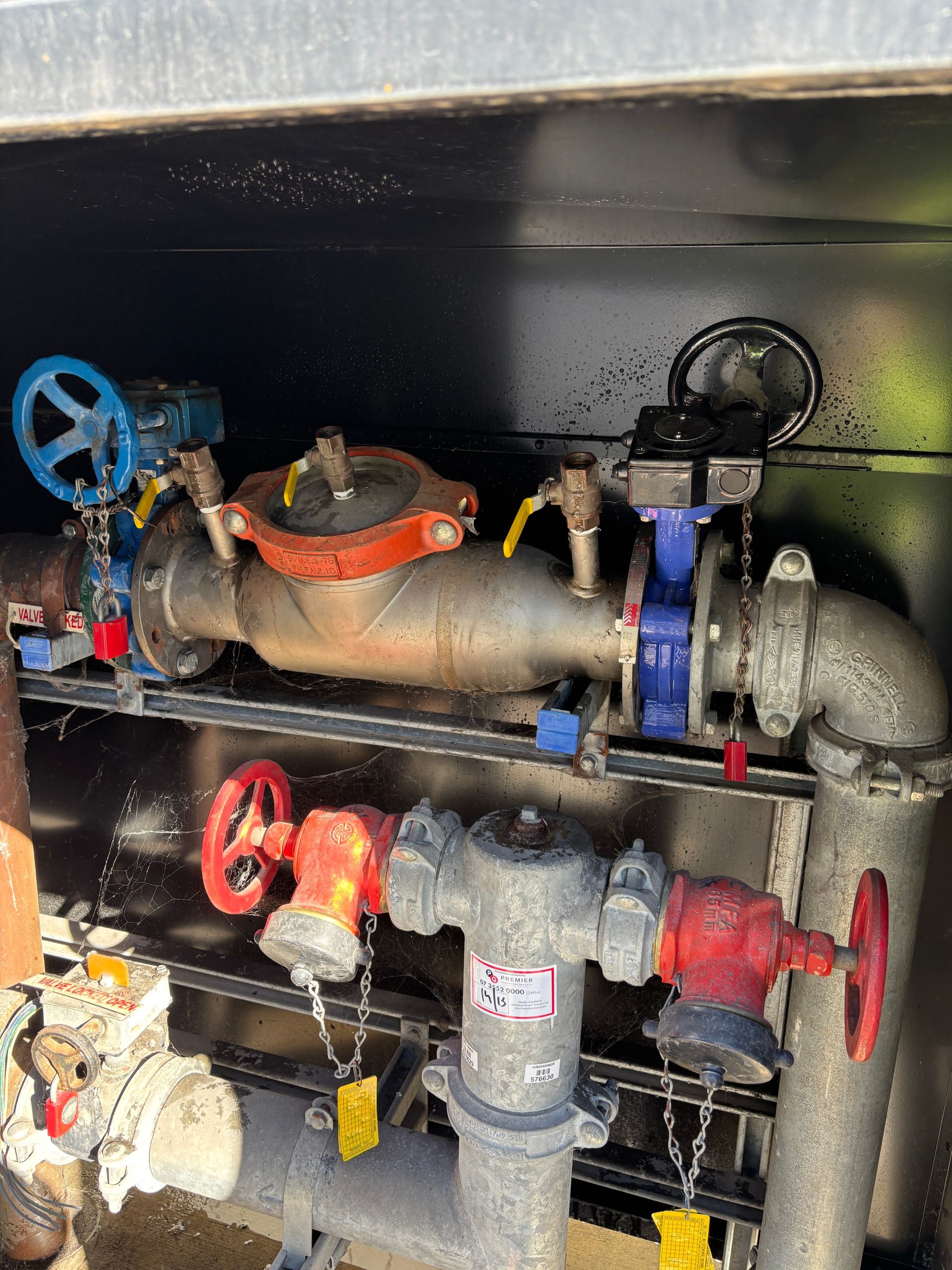 Pipes and valves inside a metal compartment. Includes blue, red, and yellow handles.