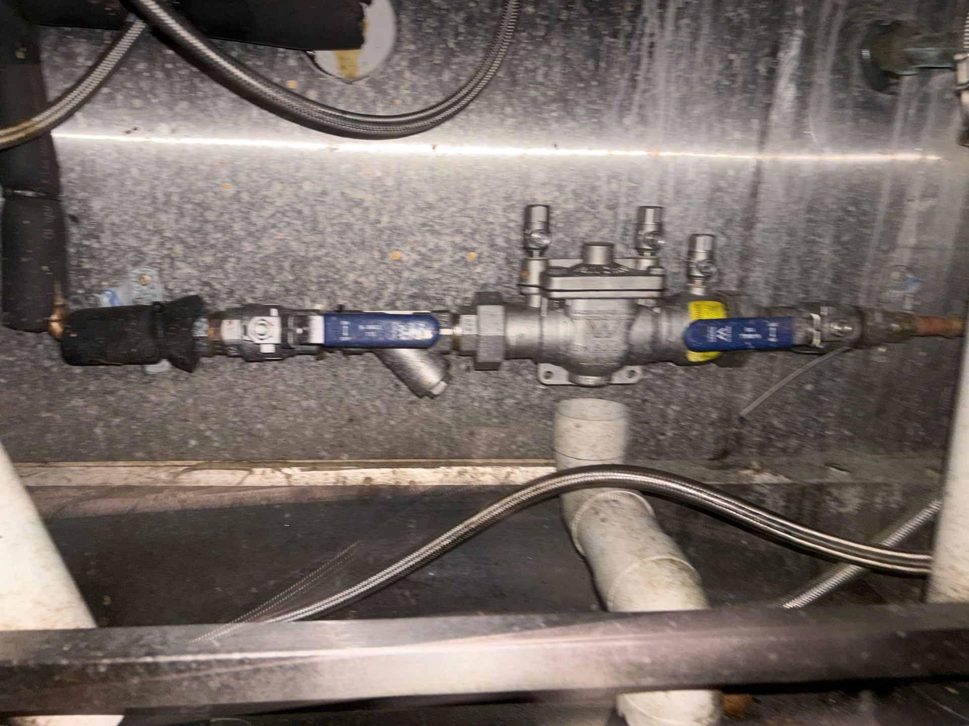 Plumbing pipes with blue valves, a filter, and insulation, set within a metal enclosure.
