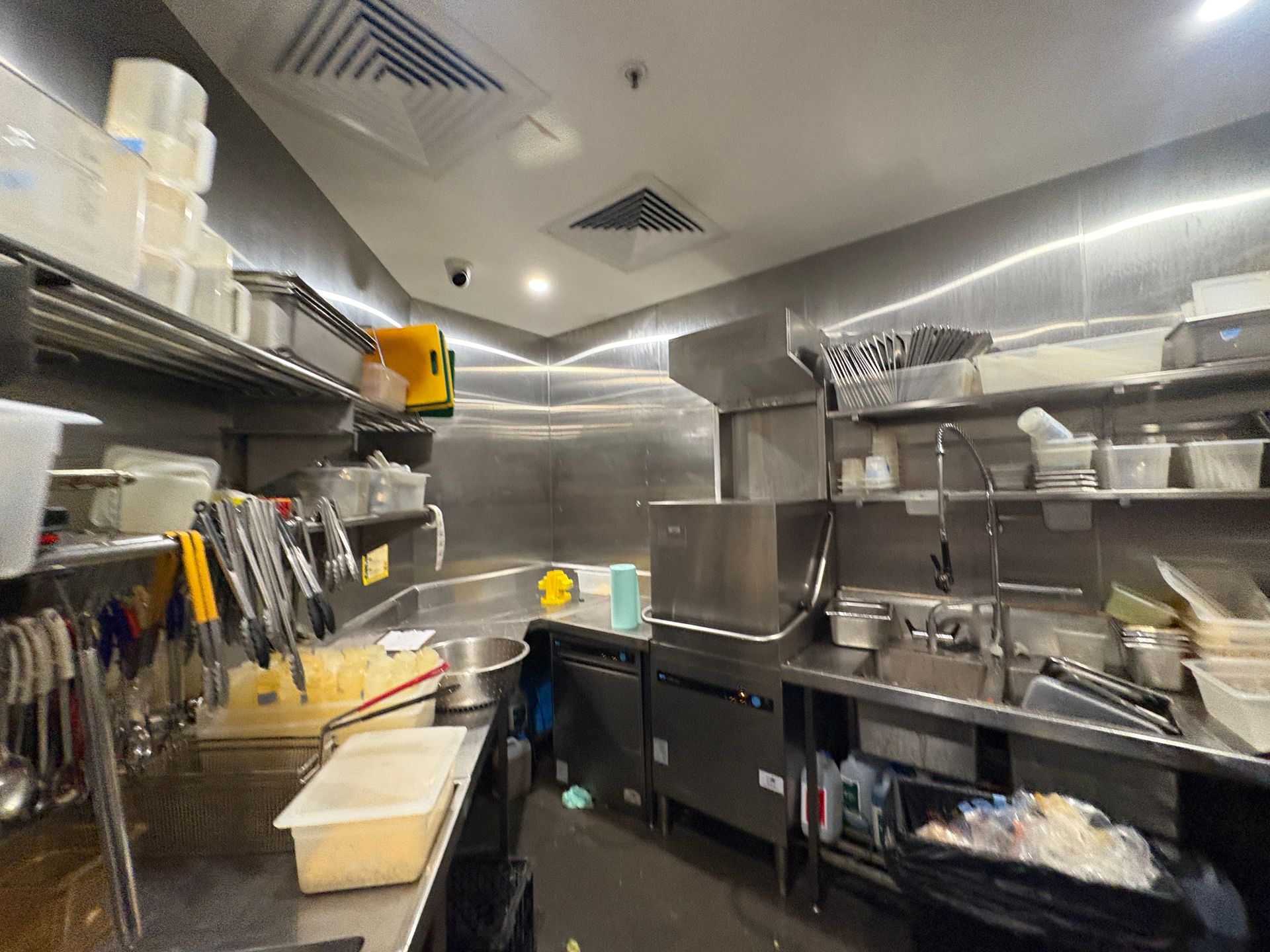 Under-sink view: black garbage disposal, white pipes, plumbing, electrical outlet, inside a white cabinet.