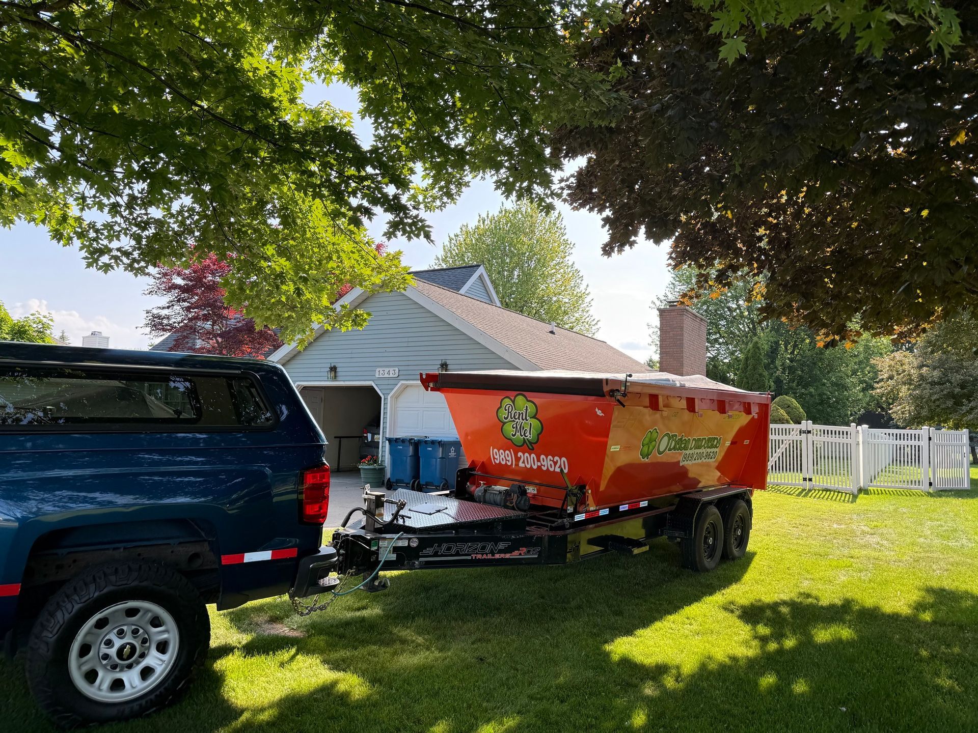 Blue truck towing a brightly colored trailer on a lawn near a house.