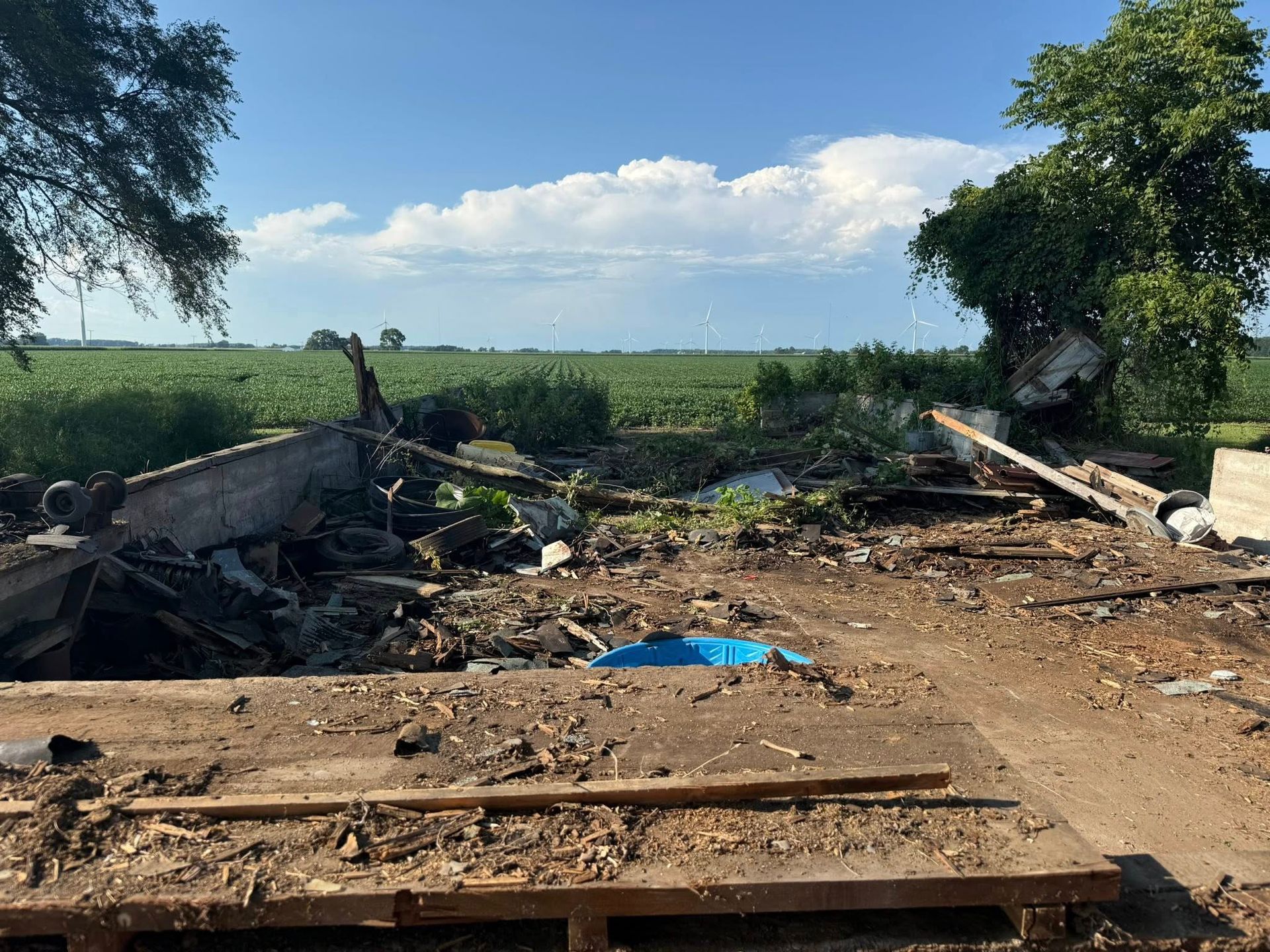 Debris scattered on dirt, field in background, sunny sky.