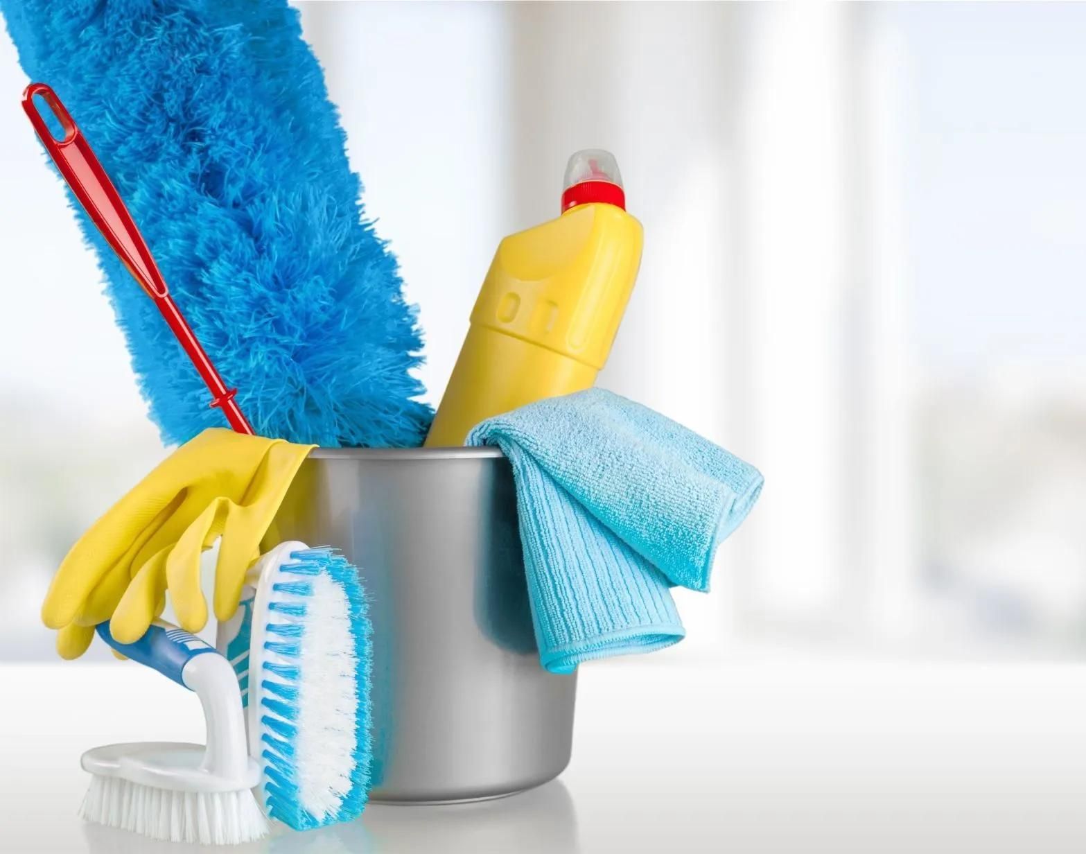 A bucket filled with cleaning supplies including gloves , brushes , and a mop.