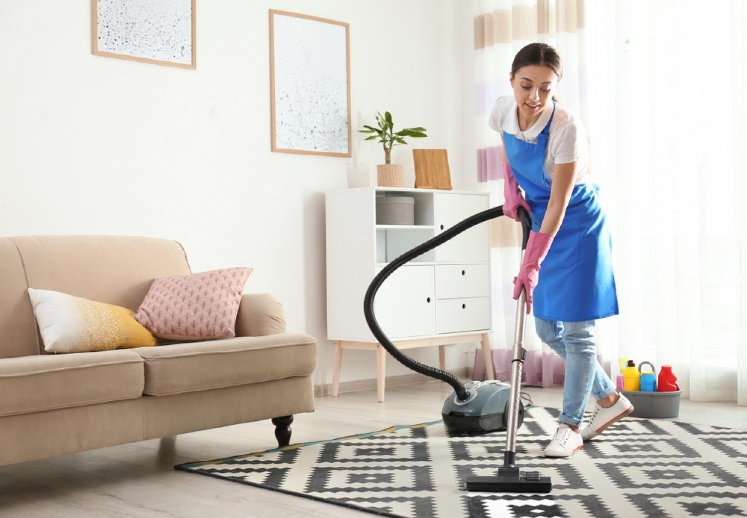 A woman is cleaning the floor with a vacuum cleaner in a living room.