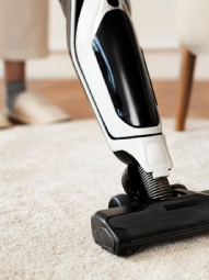 A person is using a vacuum cleaner on a carpet.