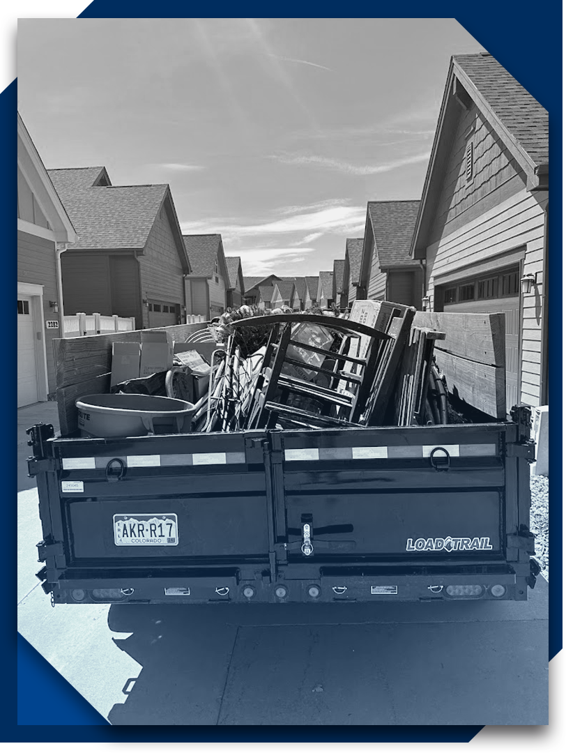 A black and white photo of a dumpster in front of a row of houses.
