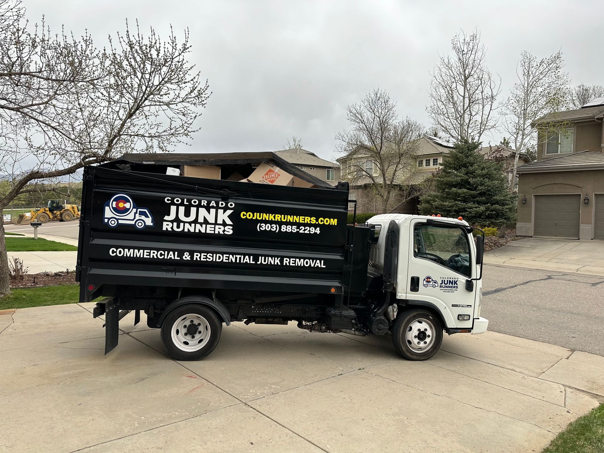 A junk runner truck is parked in the driveway of a house.