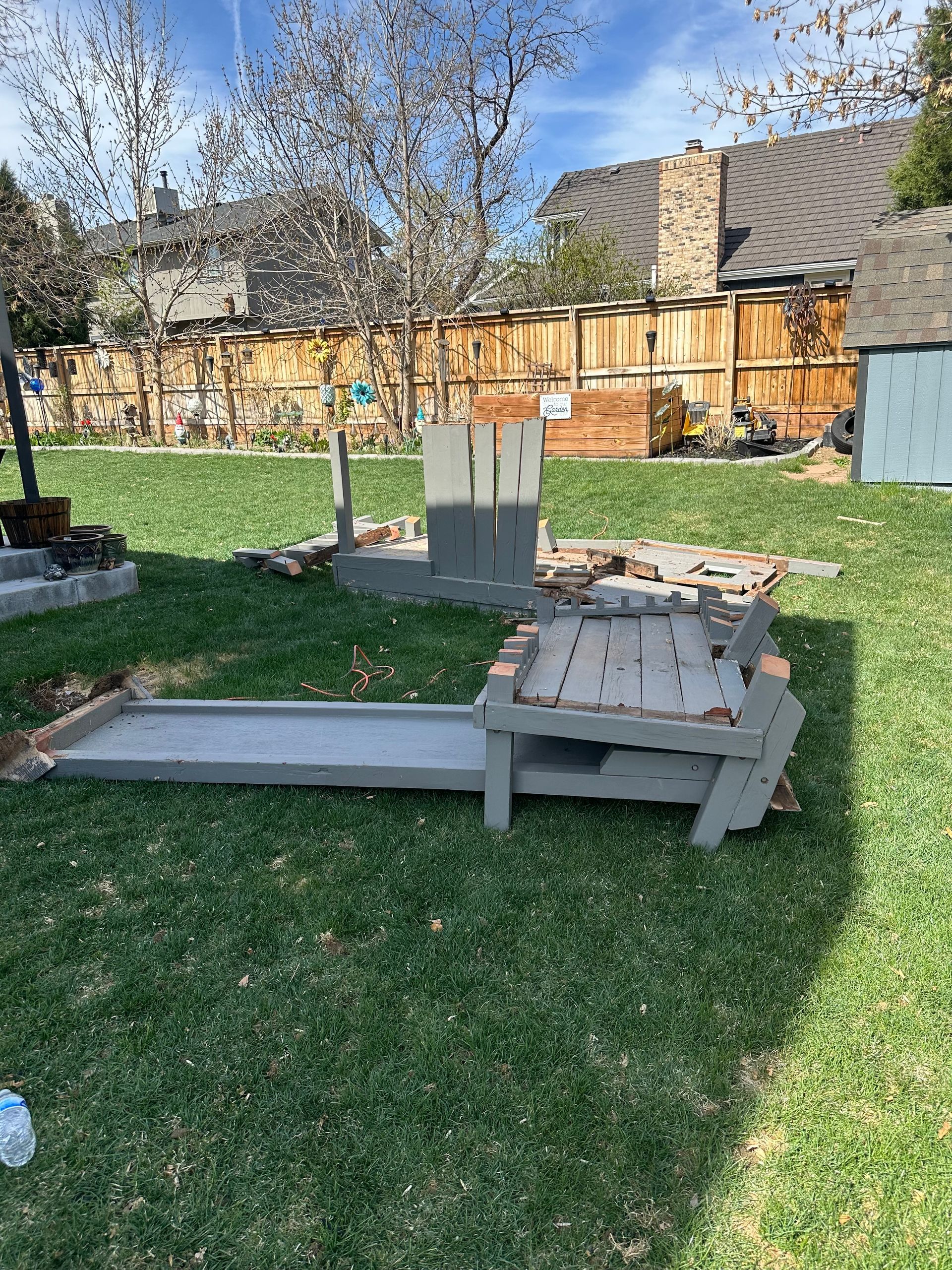 Gray wooden partially disassembled in a grassy backyard. A during picture taken in Louisville, CO