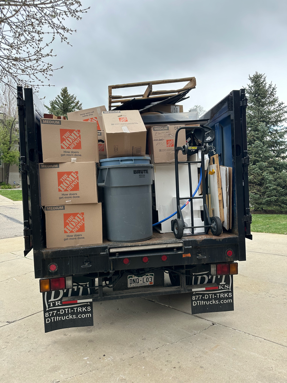 A Colorado Junk Runners truck is full of boxes and a trash can