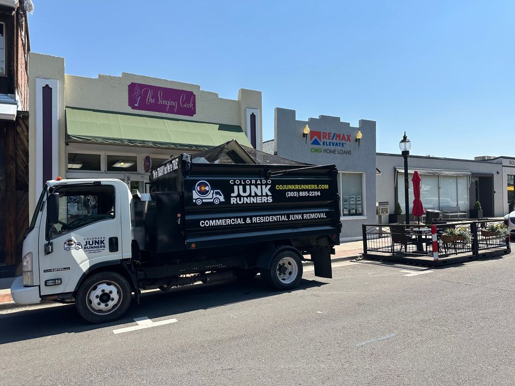 A black junk removal truck parked on a street in front of businesses in Louisville.