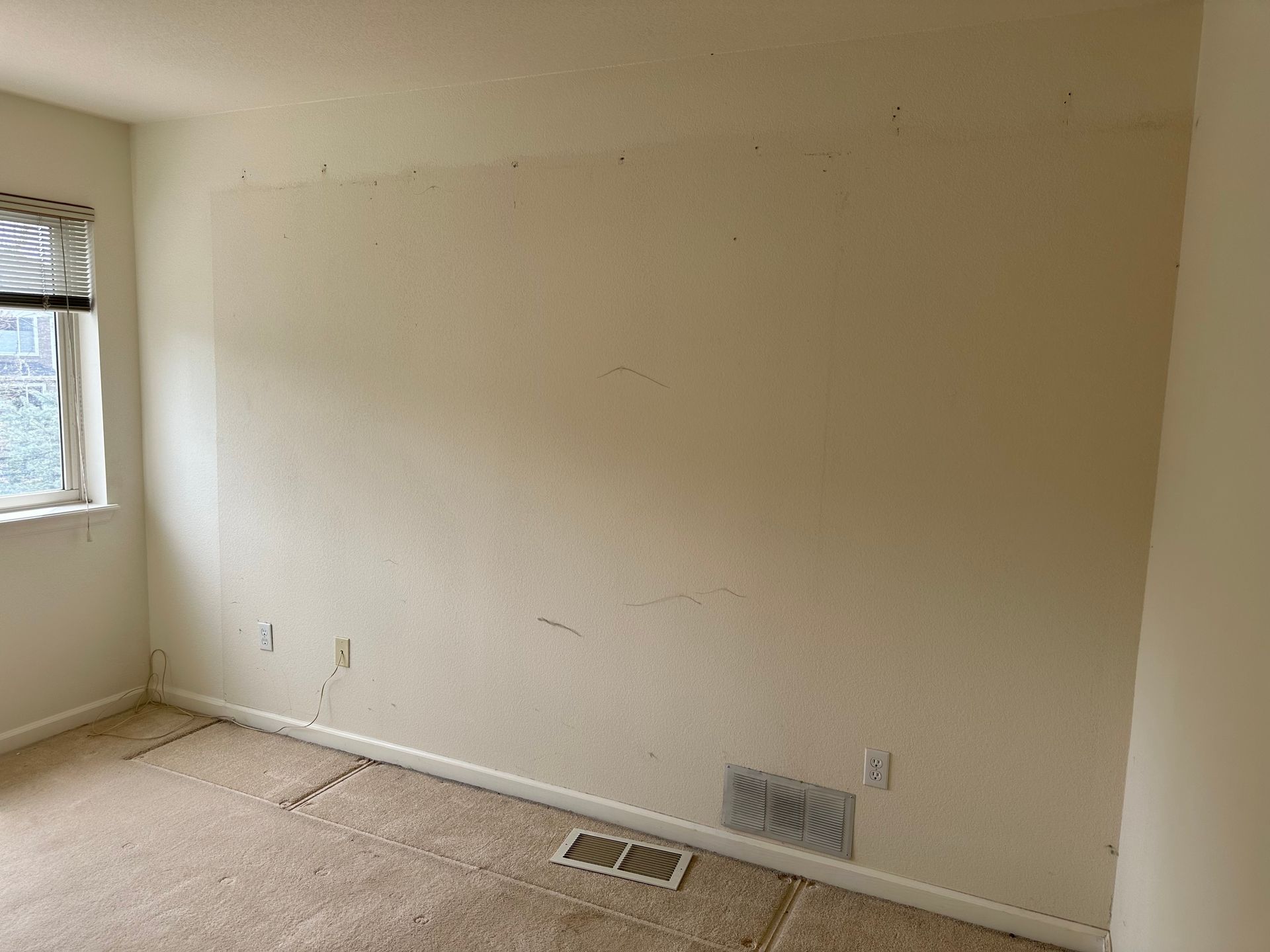 Beige room interior with a window, textured walls, and carpeted floor. An after picture taken in Arvada, CO.