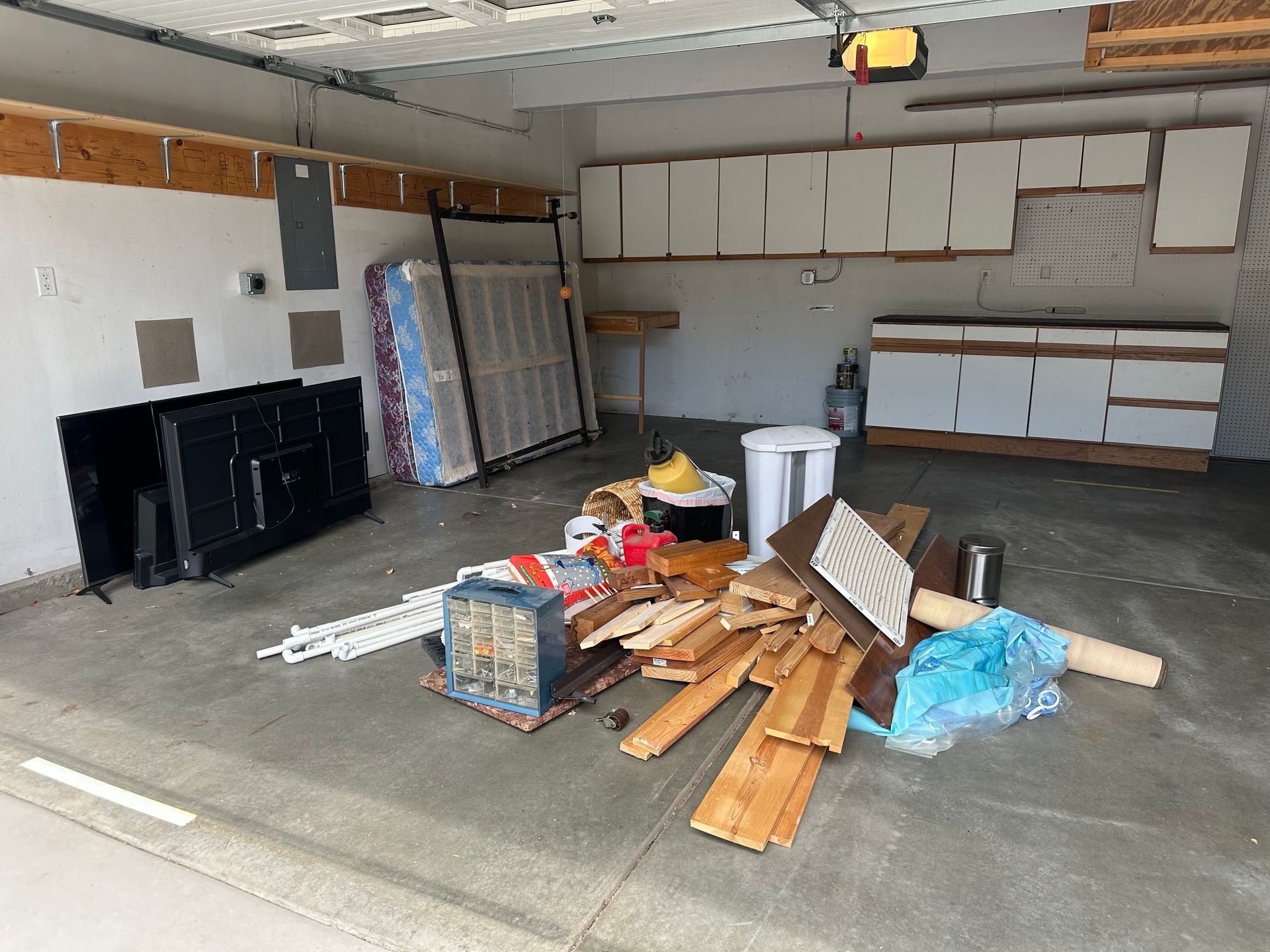 Messy garage interior with furniture, debris, and cabinets. A before picture taken in Boulder, CO.