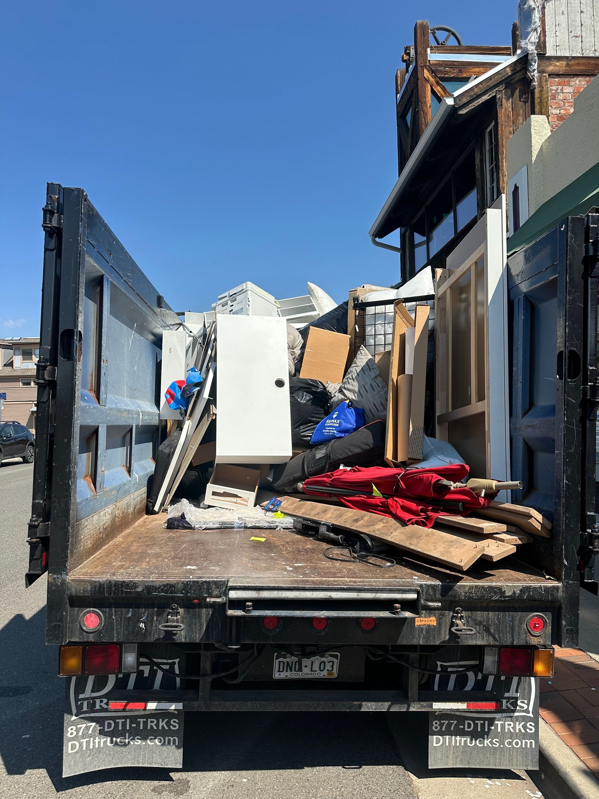 Junk truck filled with construction debris parked on a city street.