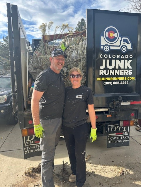 A man and woman standing in front of a junk runner truck