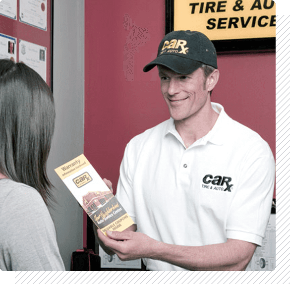 Car X employee smiling, handing a brochure to a customer in a tire shop; red wall, cap, logo.