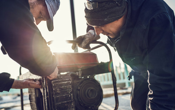 Two men are working on a generator together.