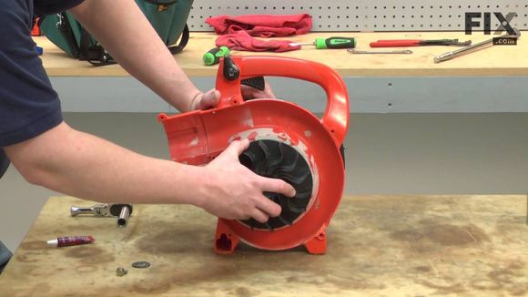 A man is fixing a blower on a wooden table.