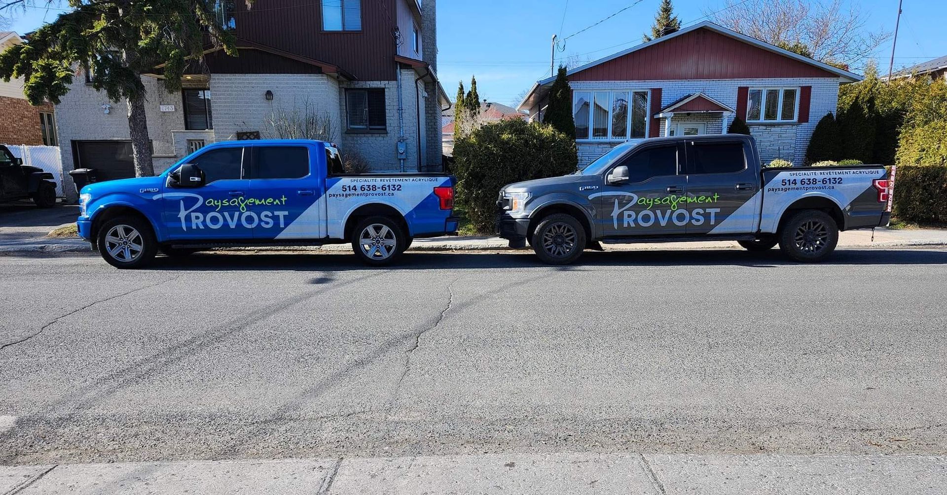Deux camions de service stationnés dans une rue, devant des maisons.