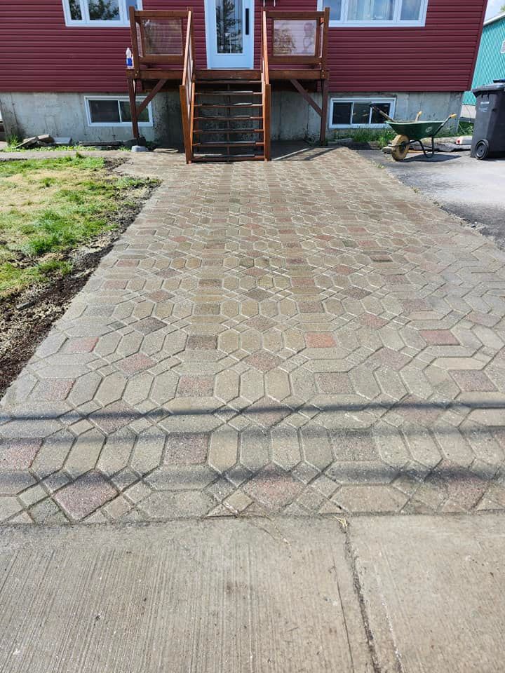 Allée en briques menant à une maison rouge avec escalier et porte en bois.