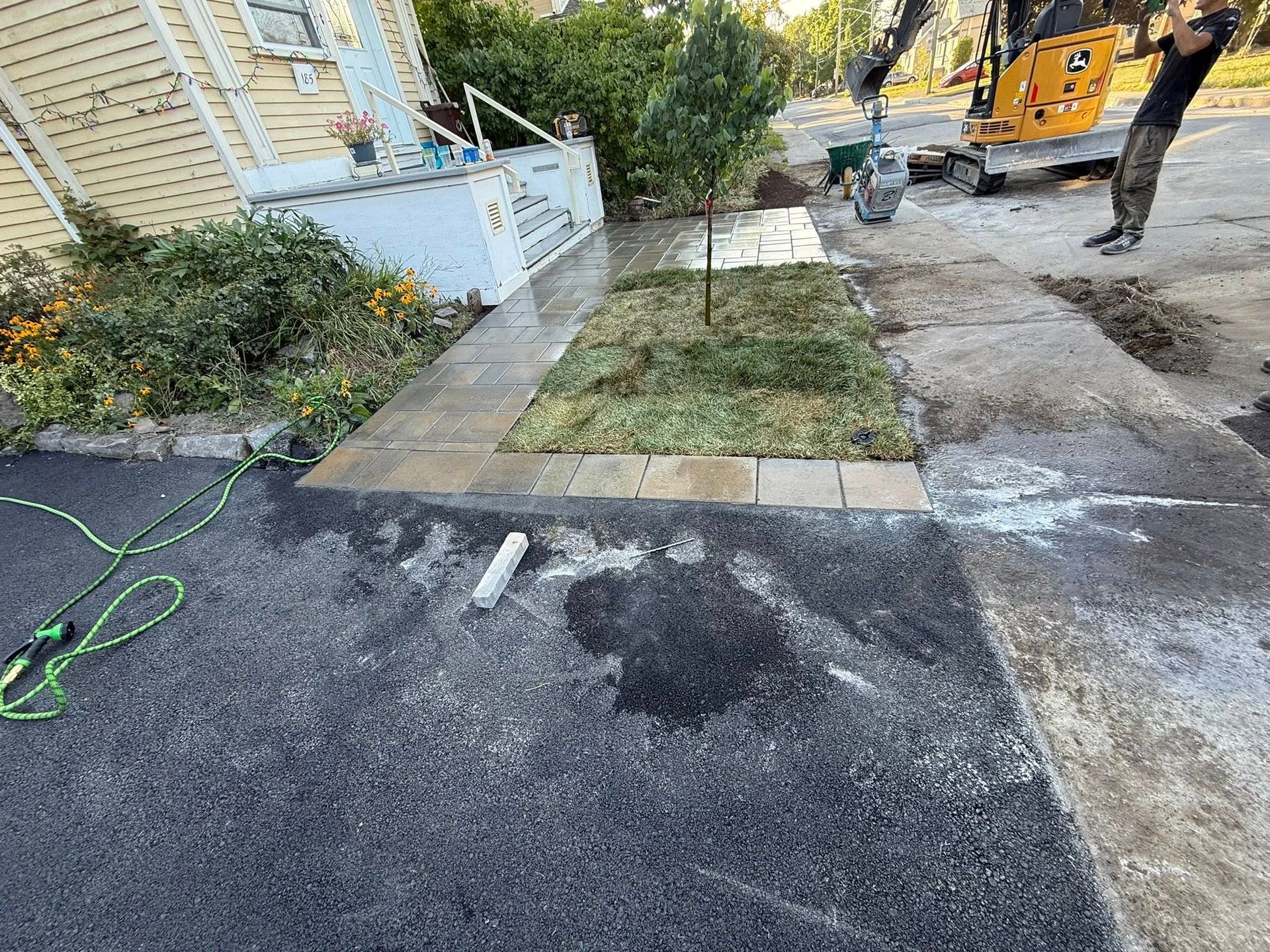 Un parterre de jardin nouvellement aménagé sur une surface pavée à côté d'un bâtiment.