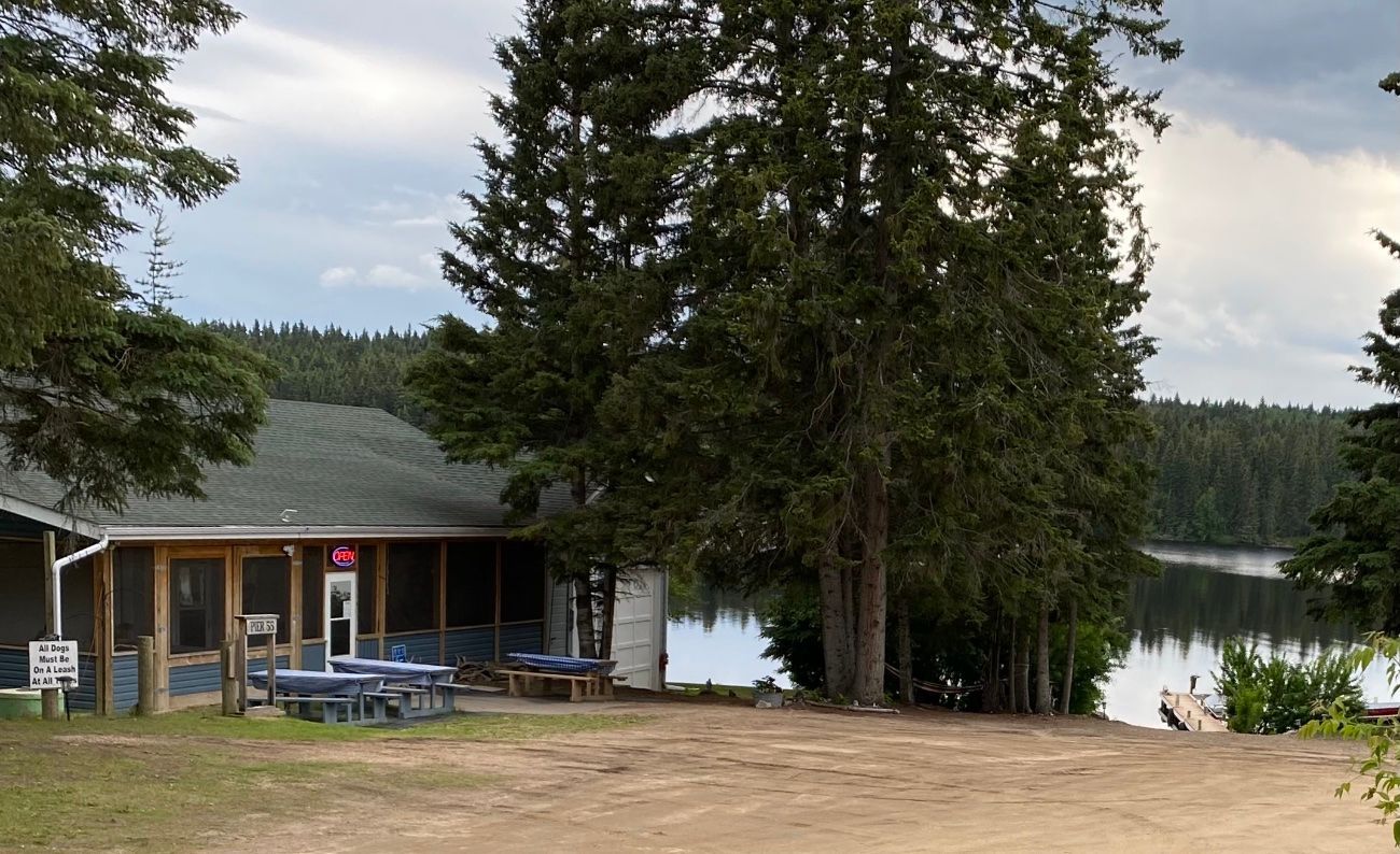 A house with tables and chairs in front of a lake