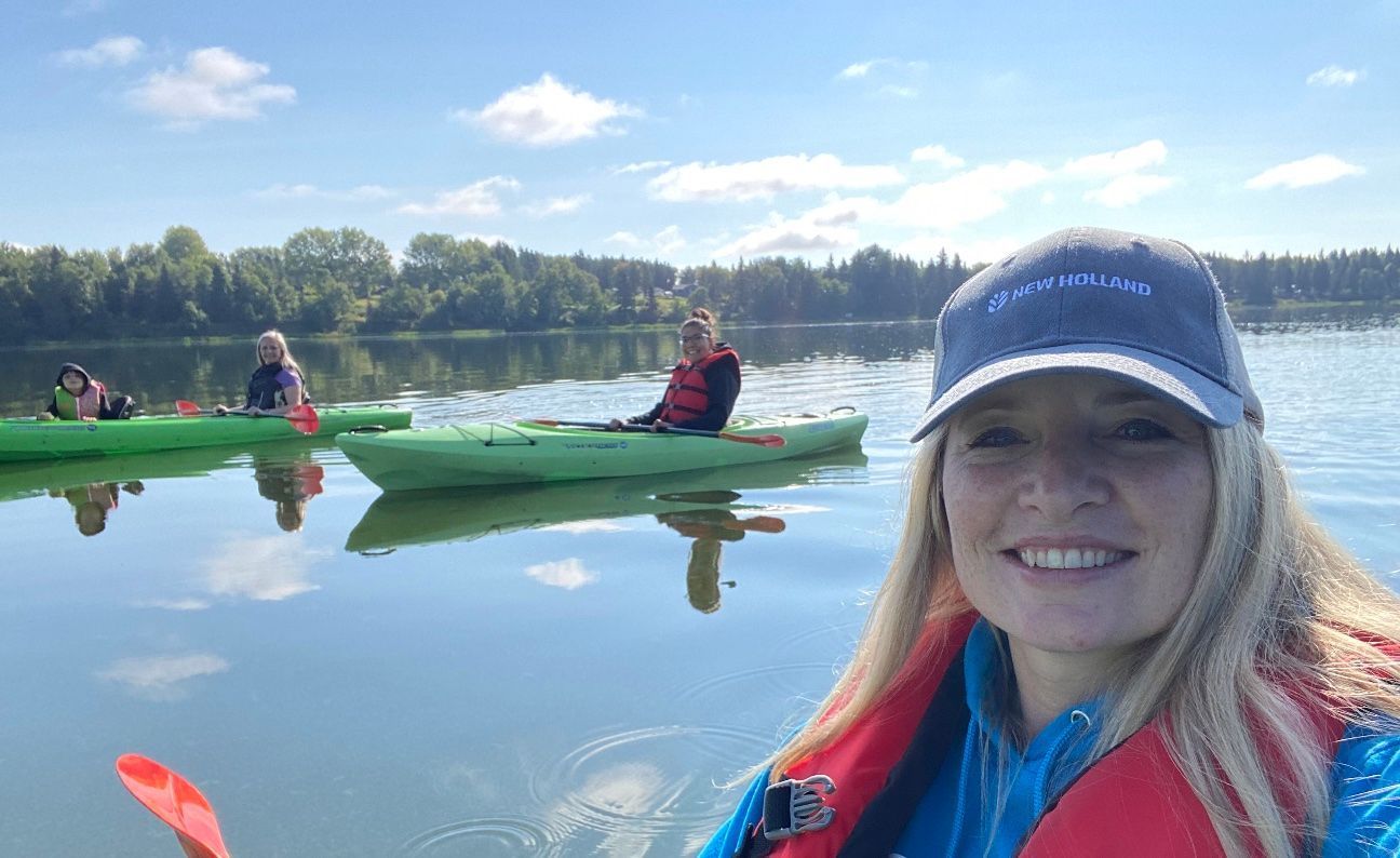 A woman is taking a selfie in a kayak on a lake.